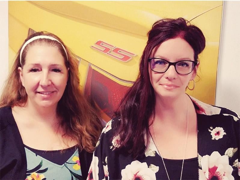Two girls stand in front of a yellow background