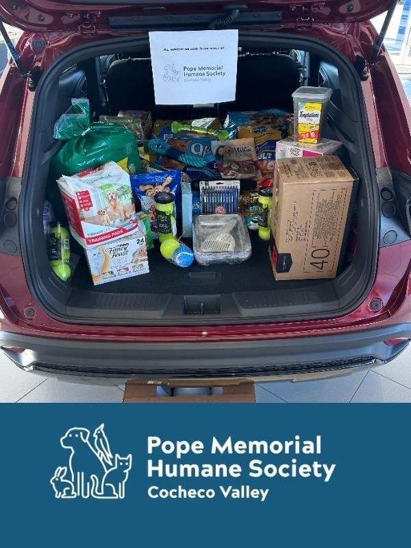 pen trunk of a red vehicle filled with donations. Sign reads Pope Memorial Humane Society Cocheco Valley Logo below.